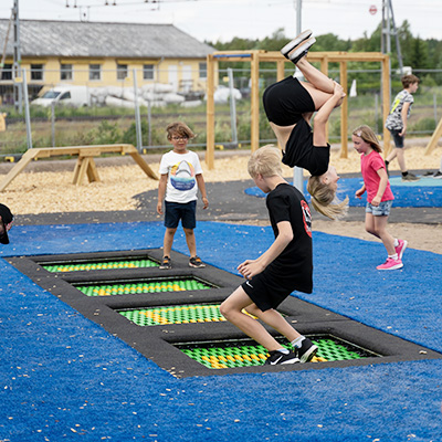 Des enfants jouent sur des trampolines au sol dans une aire de jeux.